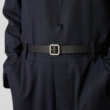 Front view of black marsell quadra belt on model wearing black shirt and trousers, against a white background.