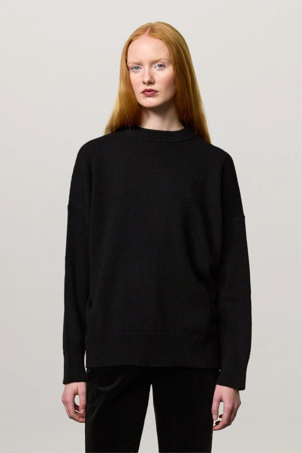 Front view of nero amelia rn sweater on model wearing black pants, against a white background.