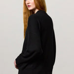 Back view of nero amelia rn sweater on model wearing black pants, against a white background.
