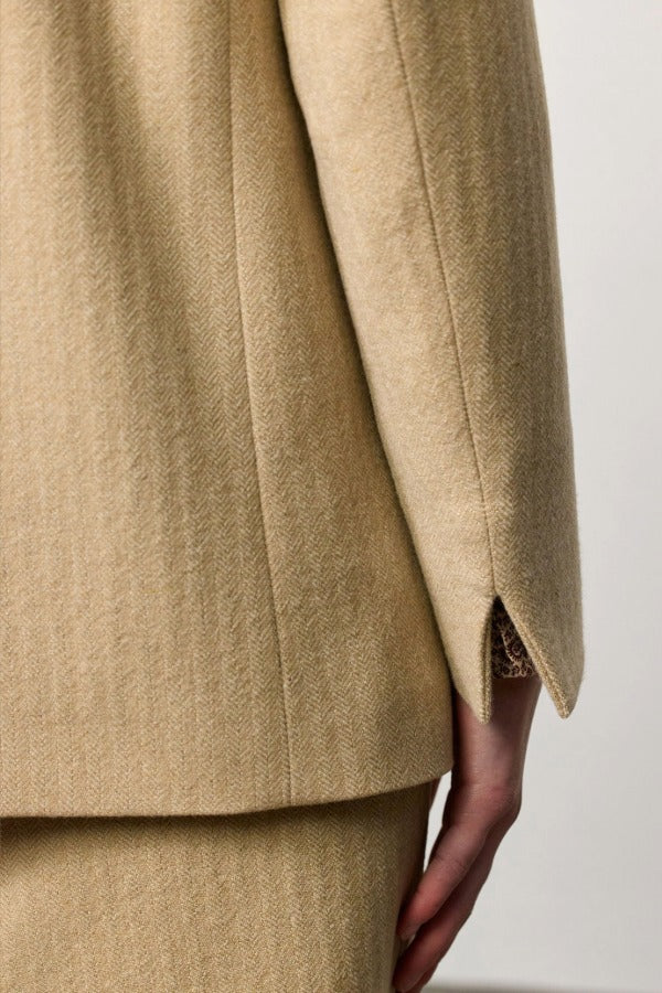 Back closeup view of naturale beatrix db jacket on model wearing naturale skirt, against a white background.