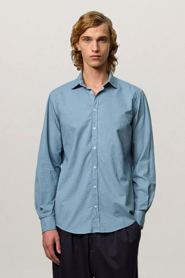 Front view of blue rain canary shirt on model wearing black trousers, against a white background.