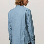 Back view of blue rain canary shirt on model wearing back trousers, against a white background.