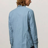 Back view of blue rain canary shirt on model wearing back trousers, against a white background.