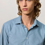 Front closeup view of blue rain canary shirt on model against a white background.