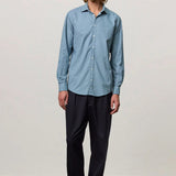 Front view of blue rain canary shirt on model wearing black trousers and brown suede shoes, against a white background.