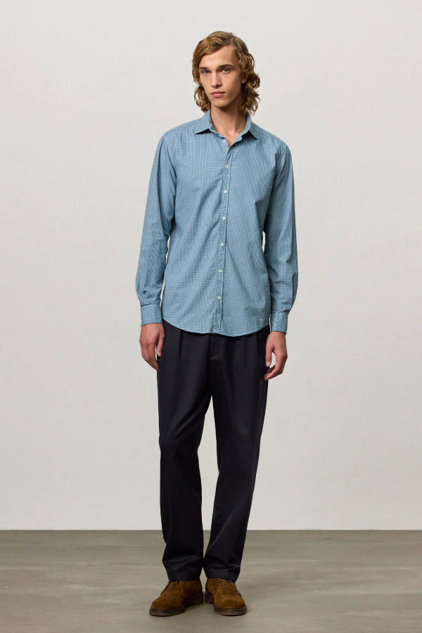Front view of blue rain canary shirt on model wearing black trousers and brown suede shoes, against a white background.