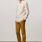 Front slanted view of saffron genova classic shirt on model wearing saffron trousers and brown suede shoes, against a white background.