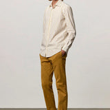 Front slanted view of saffron genova classic shirt on model wearing saffron trousers and brown suede shoes, against a white background.