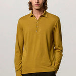 Front view of saffron ischia ls polo shirt on model wearing brown tweed trousers, against a white background.