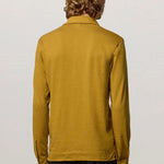 Back view of saffron ischia ls polo shirt on model wearing brown tweed trousers, against a white background.