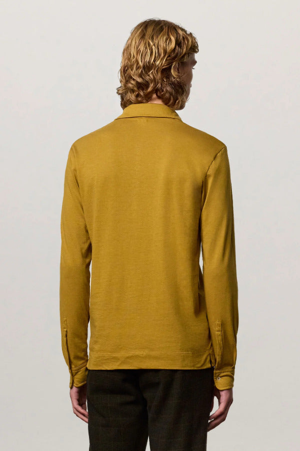 Back view of saffron ischia ls polo shirt on model wearing brown tweed trousers, against a white background.