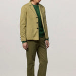 Front slanted view of verde baglietto blazer on model wearing green sweater underneath and green corduroys, against white background
