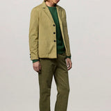 Front slanted view of verde baglietto blazer on model wearing green sweater underneath and green corduroys, against white background