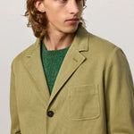 Front closeup view of verde baglietto blazer on model wearing green sweater underneath, against a white background.