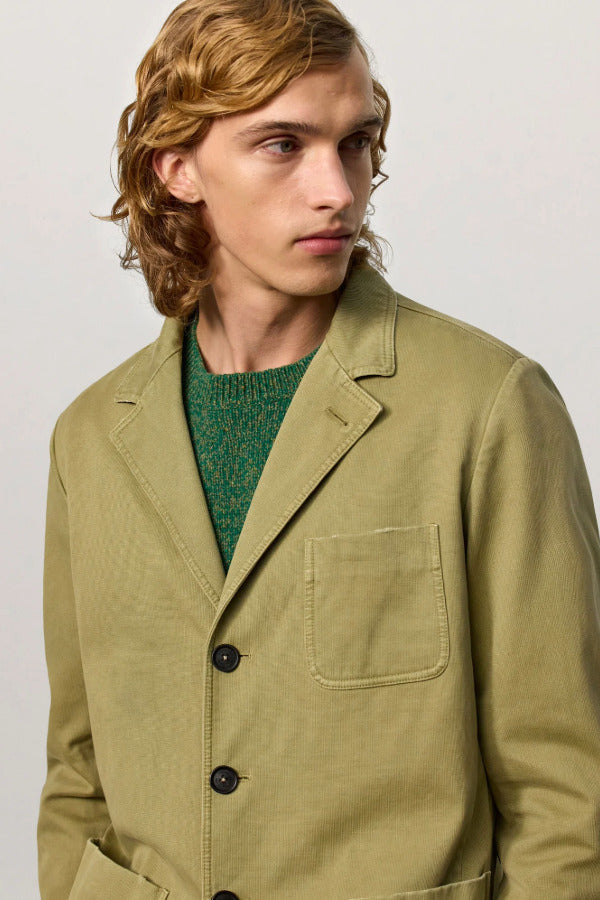 Front closeup view of verde baglietto blazer on model wearing green sweater underneath, against a white background.