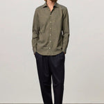 Front view of verde genova classic shirt on model wearing black trousers and brown suede shoes, against a white background.