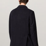 Back view of blue brando db blazer on model wearing yellow pants, against a white background.
