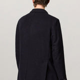Back view of blue brando db blazer on model wearing yellow pants, against a white background.