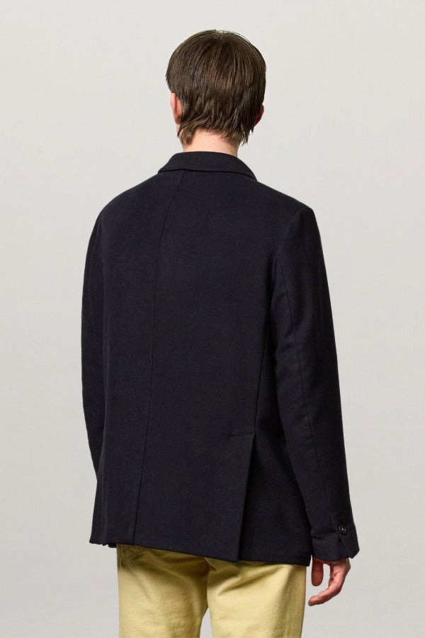 Back view of blue brando db blazer on model wearing yellow pants, against a white background.