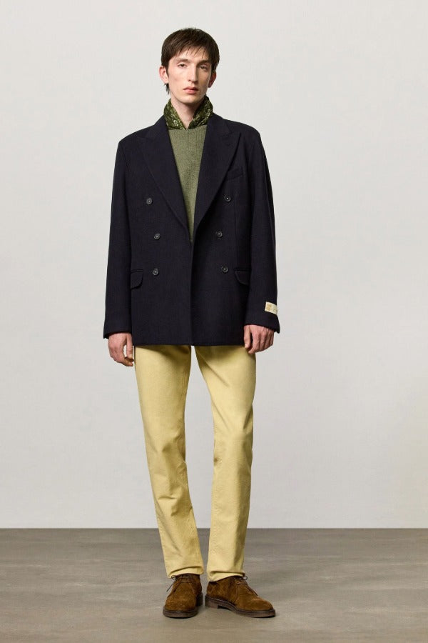 Front view of blue brando db blazer on model wearing green t-shirt, yellow pants and boots, against a white background.