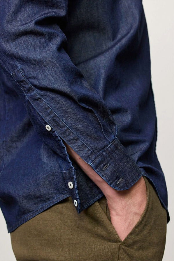 Side closeup view of blu canary classic shirt on model wearing green pants, against a white background.