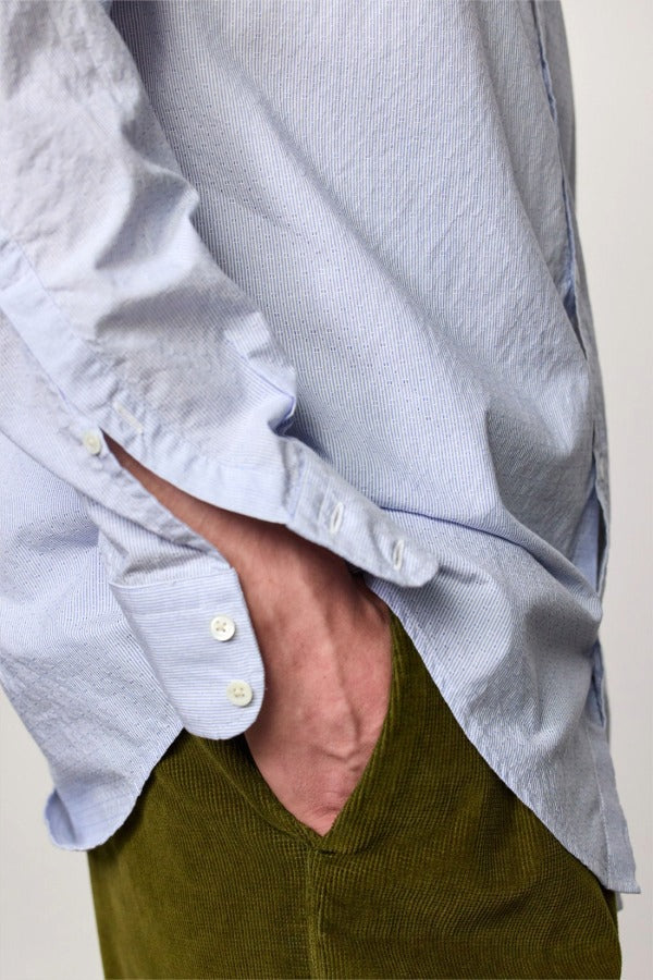 Side closeup view of azzurro canary classic shirt on model wearing green pants, against a white background.