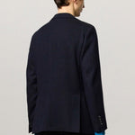 Back view of blue catch2 jacket on model wearing blue pants, against a white background.