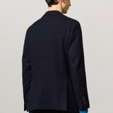 Back view of blue catch2 jacket on model wearing blue pants, against a white background.