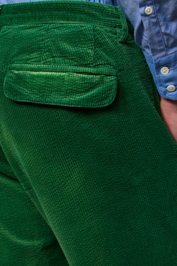 Back closeup view of green ionio2 trouser on model wearing blue shirt, against a white background.