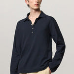 Front view of dark blue ischia ls polo shirt on model wearing milk pants, against a white background.