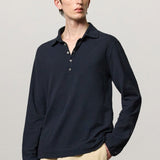 Front view of dark blue ischia ls polo shirt on model wearing milk pants, against a white background.