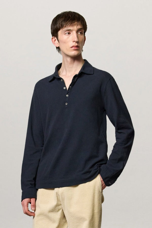 Front view of dark blue ischia ls polo shirt on model wearing milk pants, against a white background.