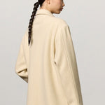 Back view of milk rouen jacket on model wearing tan pants, against a white background.