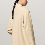 Back view of milk rouen jacket on model wearing tan pants, against a white background.