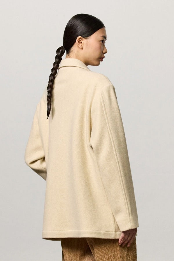 Back view of milk rouen jacket on model wearing tan pants, against a white background.