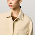 Front closeup view of milk rouen jacket on model wearing tan sweater, against a white background.