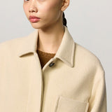 Front closeup view of milk rouen jacket on model wearing tan sweater, against a white background.