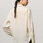 Back view of milk selma classic shirt on model wearing green pants, against a white background.