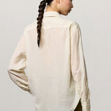 Back view of milk selma classic shirt on model wearing green pants, against a white background.