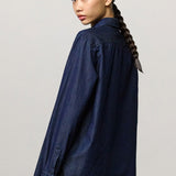 Back view of blue uma classic shirt on model wearing black pants, against a white background.