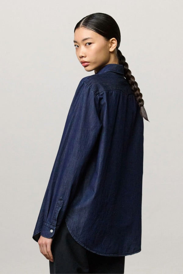 Back view of blue uma classic shirt on model wearing black pants, against a white background.