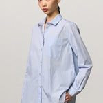 Front view of azzurro uma classic shirt on white background on model wearing grey pants, against a white background.