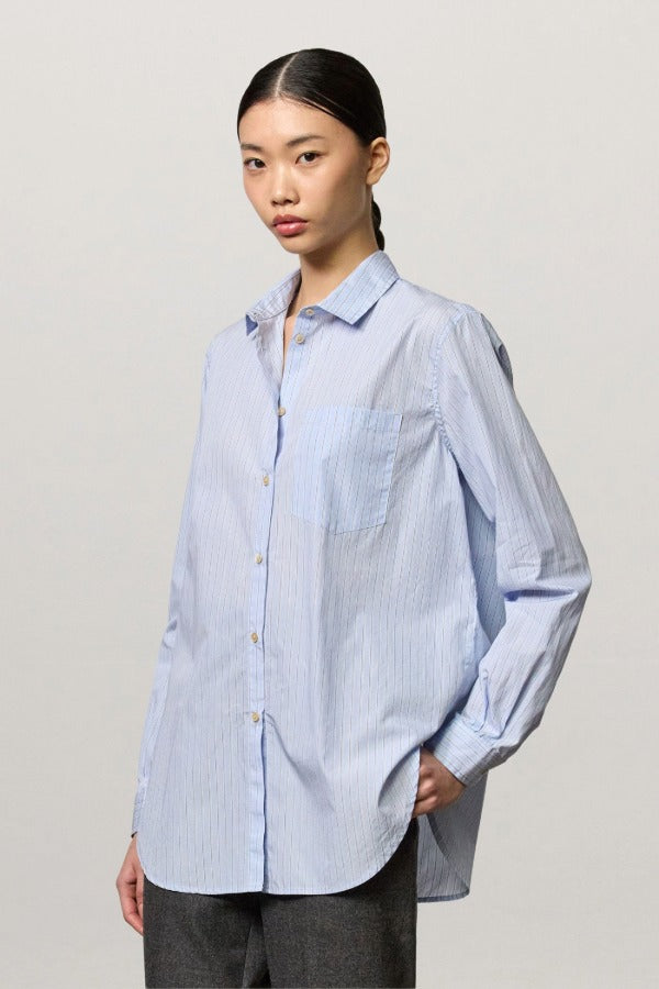 Front view of azzurro uma classic shirt on white background on model wearing grey pants, against a white background.