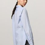 Back view of azzurro uma classic shirt on modeh wearing grey pants, against a white background.