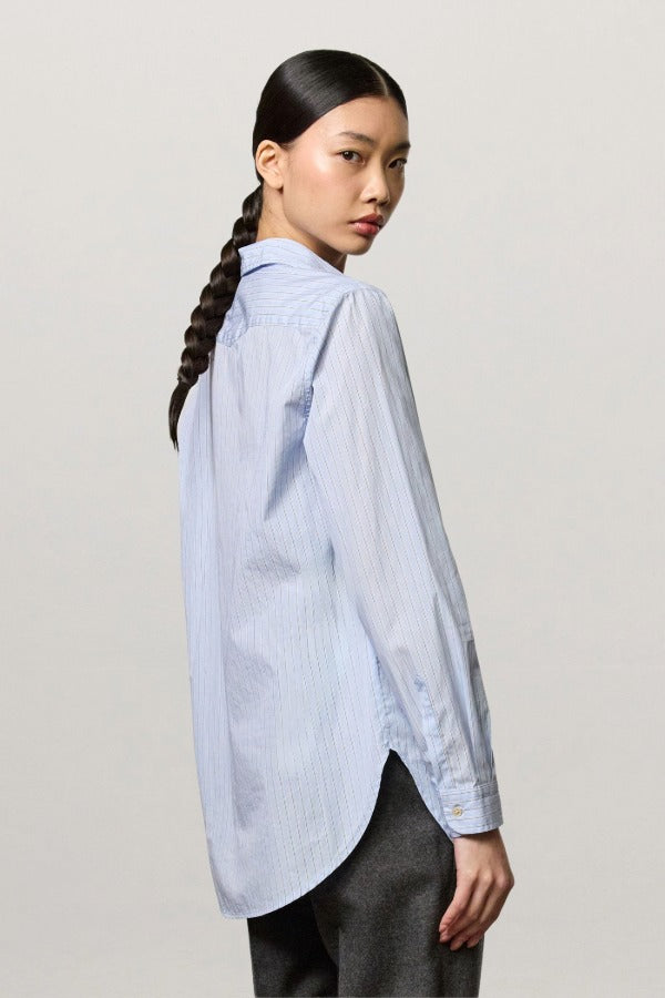 Back view of azzurro uma classic shirt on modeh wearing grey pants, against a white background.