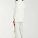 Back view of off white button embroidered sb jacket on model wearing matching pants and sneakers, against a white background.