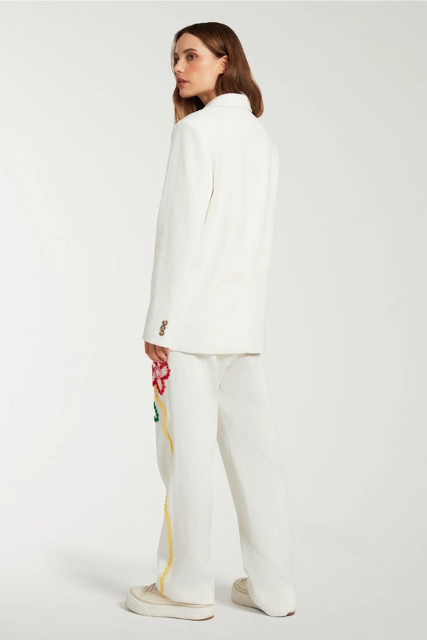 Back view of off white button embroidered sb jacket on model wearing matching pants and sneakers, against a white background.