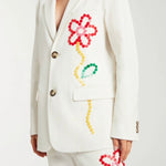 Front closeup view of off white button embroidered sb jacket on model wearing matching pants, against a white background.