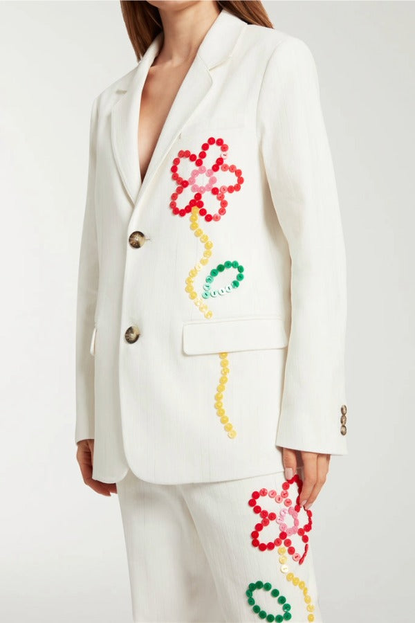 Front closeup view of off white button embroidered sb jacket on model wearing matching pants, against a white background.