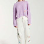 Front view of white straight leg jean on model wearing purple sweater and white sneakers, against a white background.